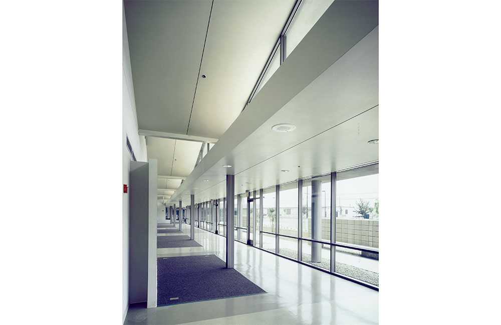 Image 5. Interior hallway showing the underside of the folded plate roof above and full height storefront system along the right.
