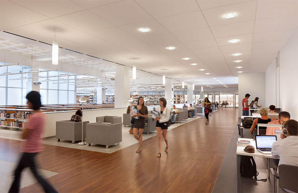 Image 4. Second floor corridor area with grey modern modular chairs located along the left side and small tables and chairs located along the right.