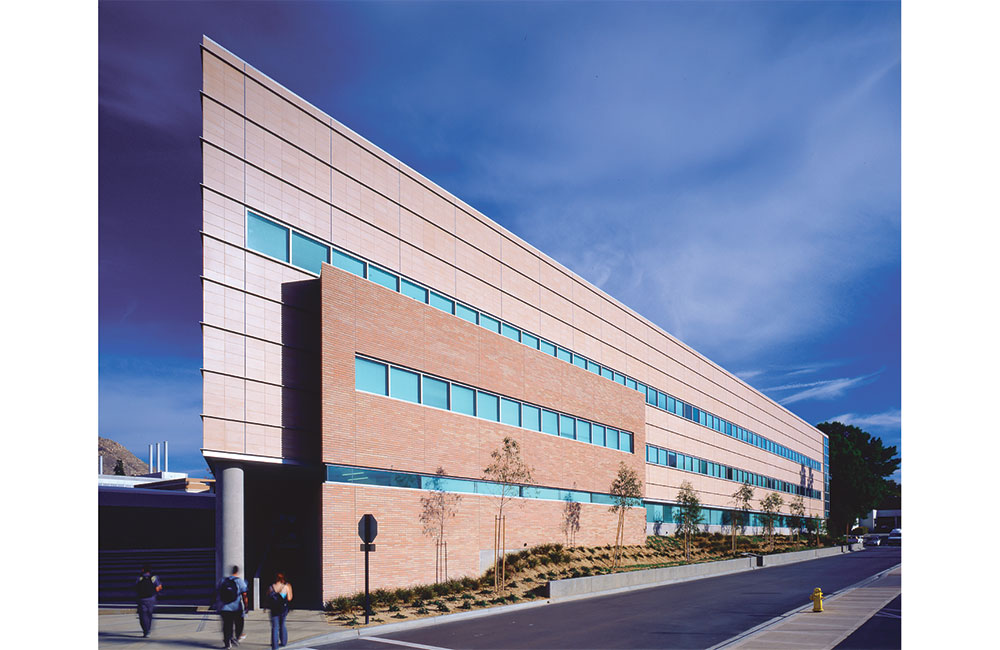 Image 2. 3-story modern building clad with sandstone-colored bricks and tiles. Ribbon windows run horizontally along the length of the building on each floor.