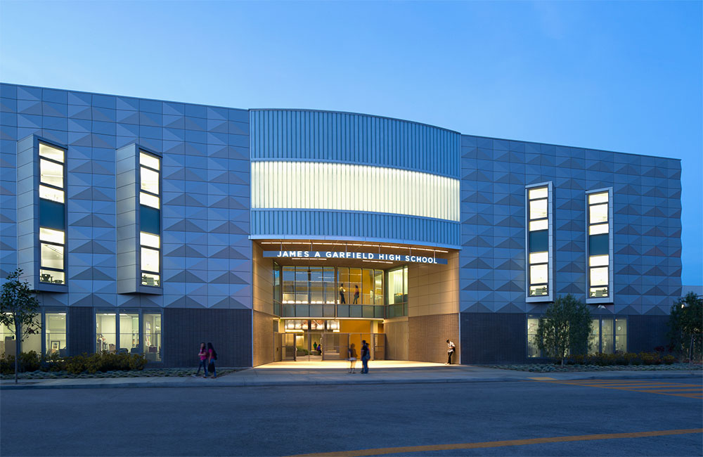 Image 6. Dusk view of building entrance showing warm glow emanating from the entry lobby and angled slot windows on second and thrid floors.